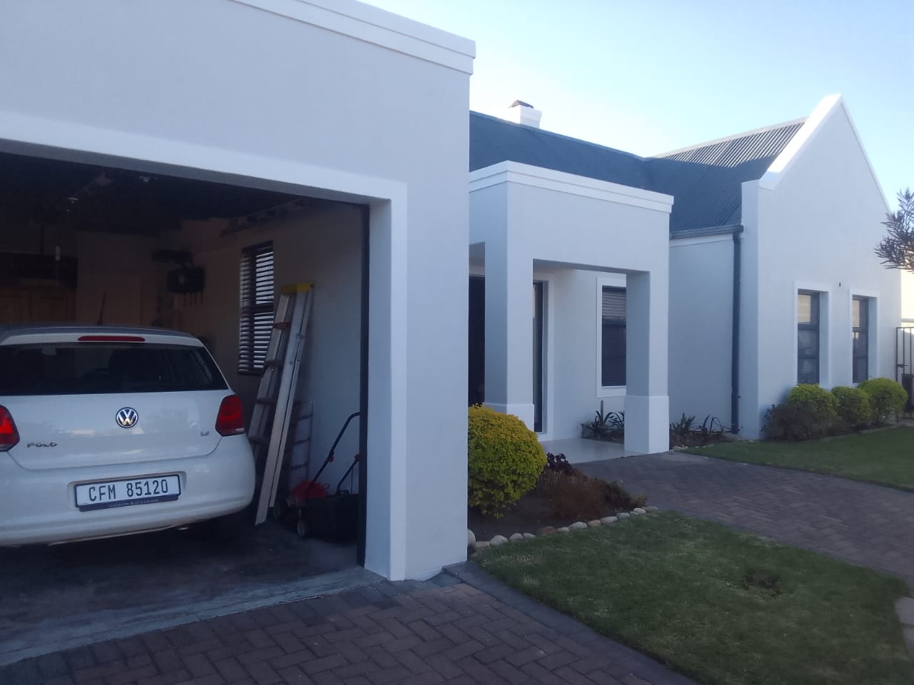 Finished crisp-white house exterior with a dark roof and a tidy garden
