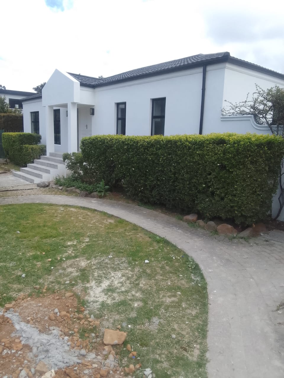Completed exterior repaint, white walls with a charcoal roofline and trimmed hedge