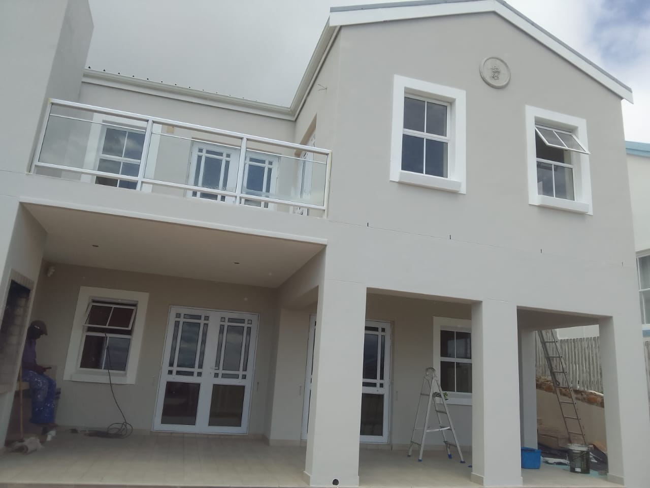 Double-storey home exterior in grey with white window trim and a glass balustrade balcony