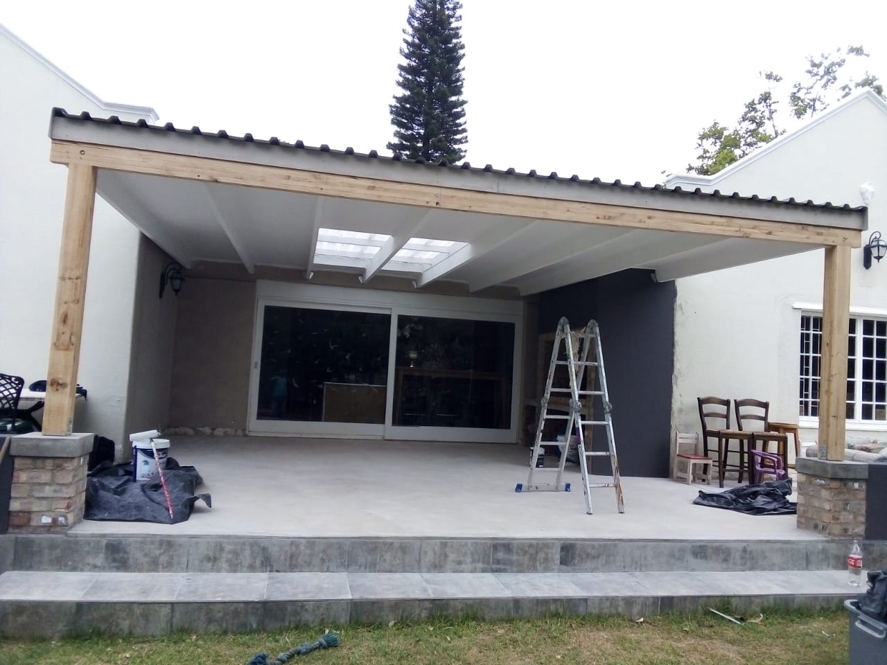 Covered veranda with a white-painted ceiling and a grey feature wall, mid-project