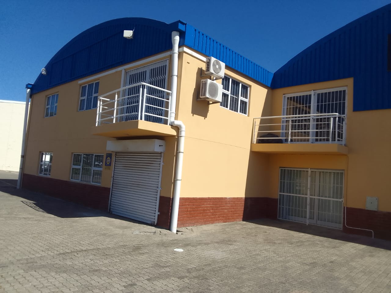 Commercial unit exterior — a blue barrel-roof warehouse with an ochre office block