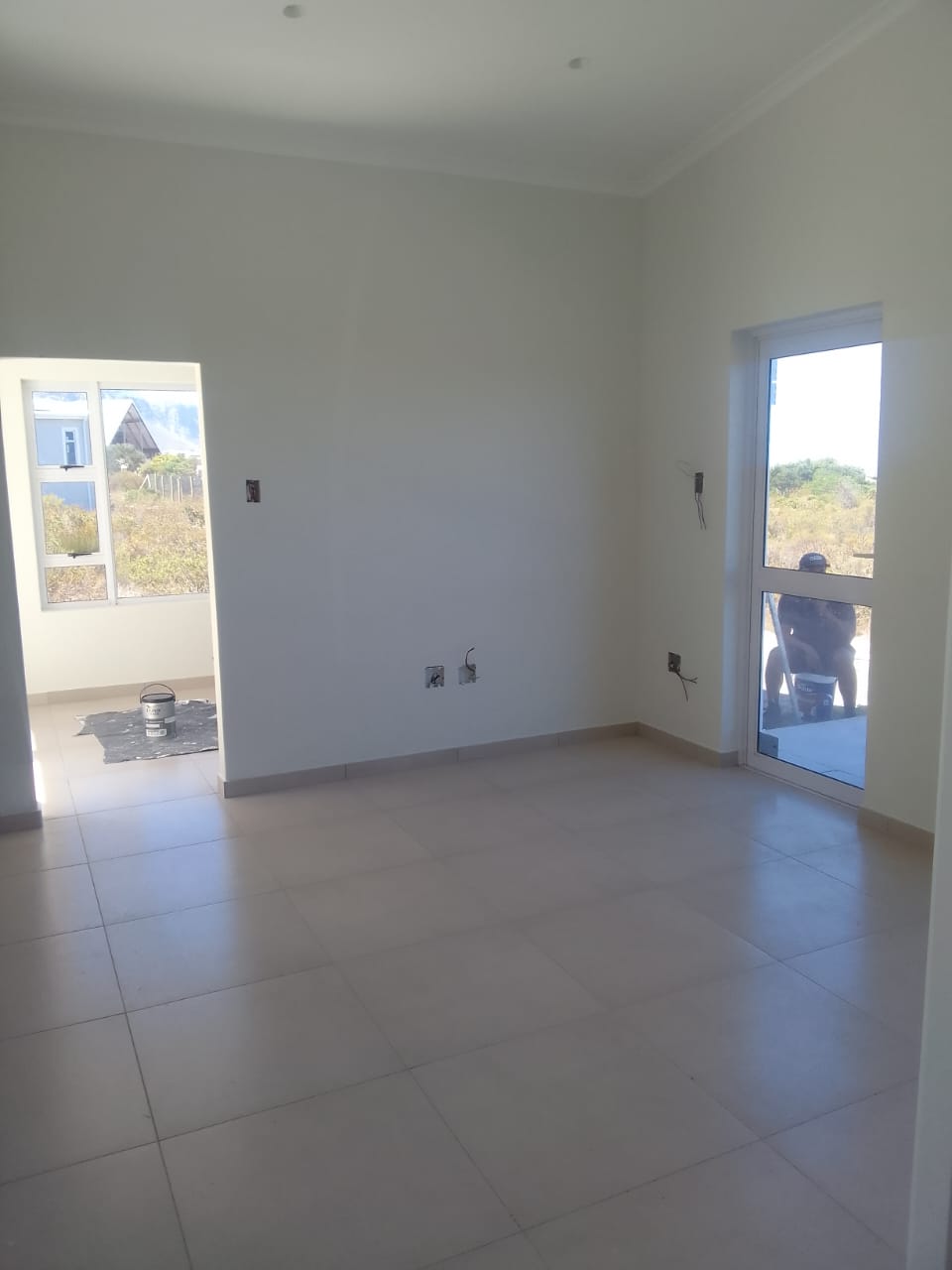 New-build interior room with freshly painted white walls and ceiling, fynbos through the window
