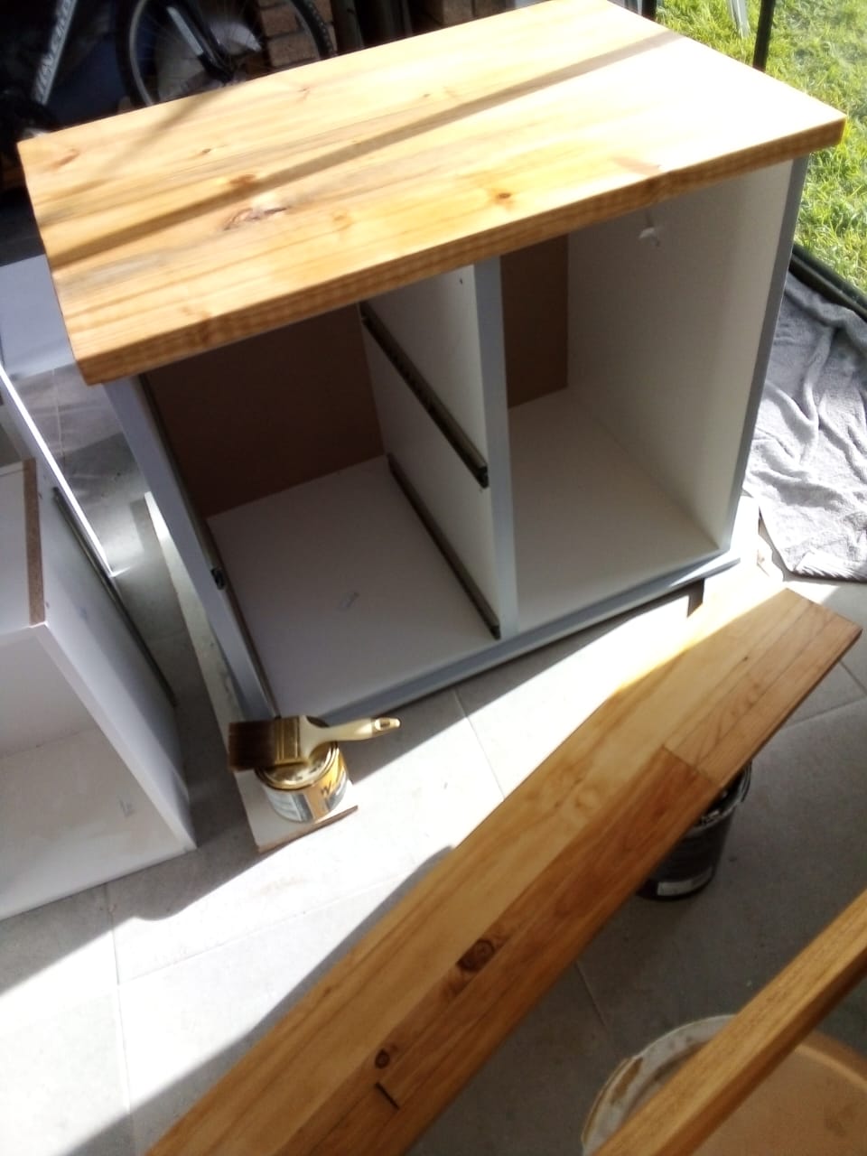 A cabinet carcass being resprayed grey with a brush resting on the paint tin