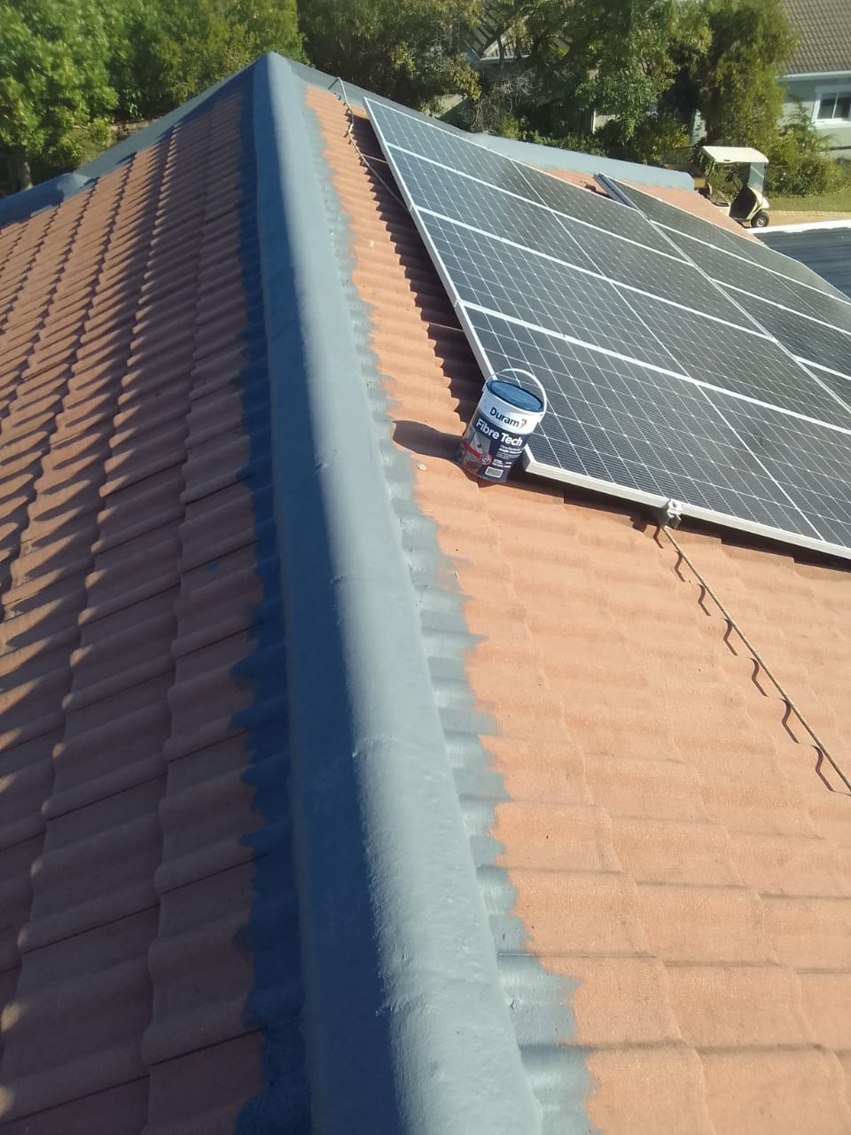 Tiled roof mid-recoat with ridges and hips sealed in grey, Duram Fibre Tech bucket and solar panels
