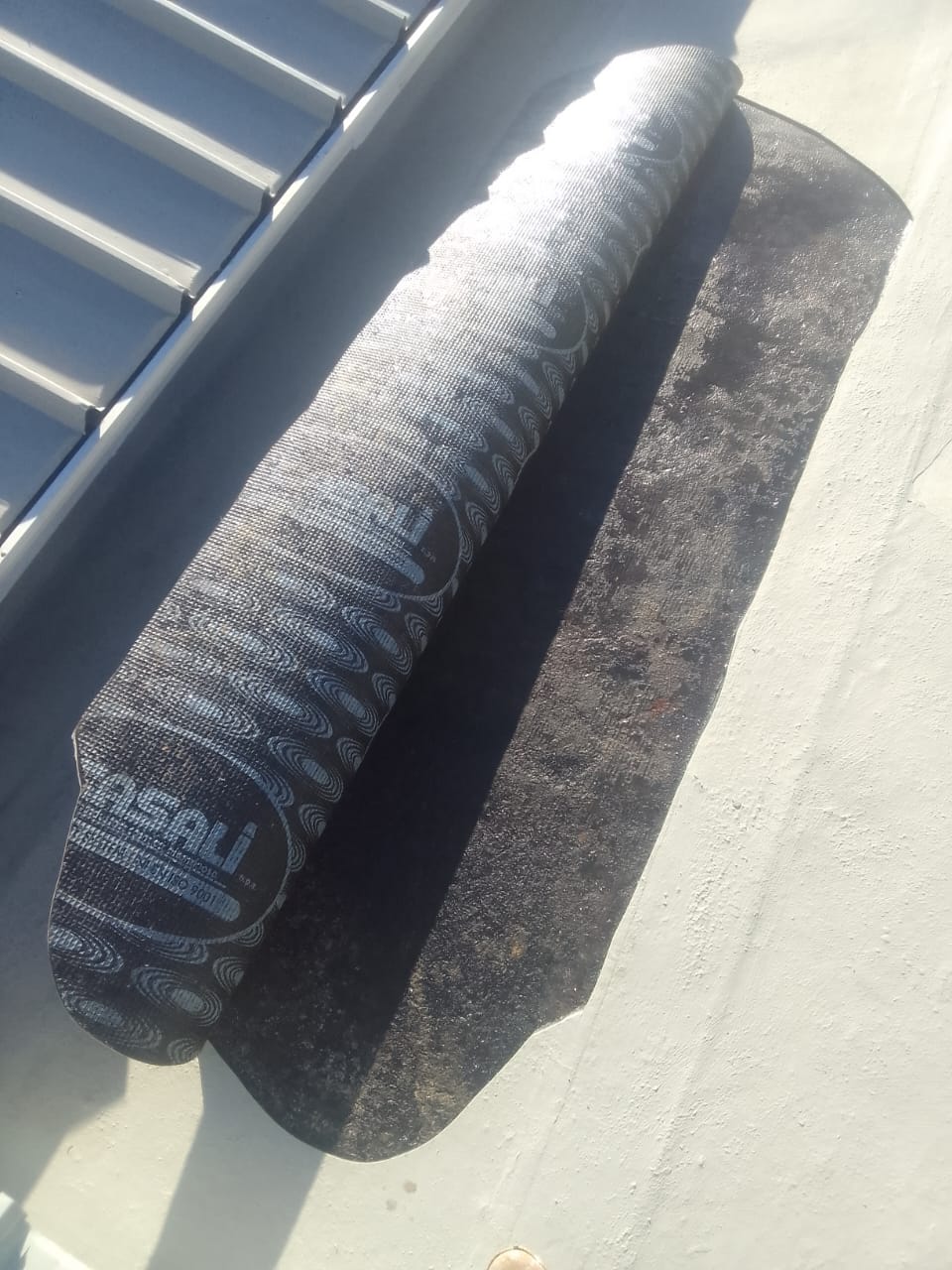 Torch-on membrane rolled out and bonded at a wall upstand on a flat roof